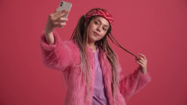 漂亮的嬉皮士女人在粉红工作室里用手机自拍 — 图库视频影像