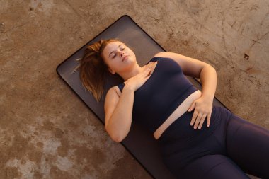 Genç kızıl kadın dışarıda yoga yaparken nefes egzersizi yapıyor.