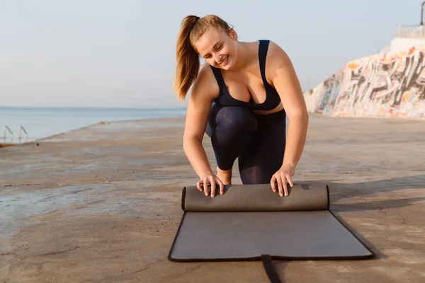 Young Ginger Sportswoman Smiling While Wringing Yoga Mat Seafront Outdoors —  Fotos de Stock