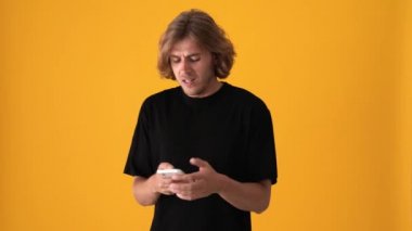 Sarı stüdyoda telefonla mesajlaşan hoşnutsuz sarışın adam.