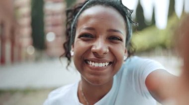 Neşeli esmer Afrikalı kadın dışarıda kameraya el sallıyor.