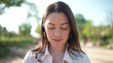 Gülümseyen esmer kadın parktaki kameraya bakıyor.