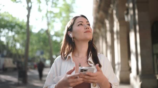 Meditativa Donna Bruna Cuffia Guardarsi Intorno Messaggiare Telefono Strada — Video Stock