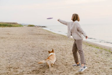 Yaşlı bir kadın kumsalda köpeğiyle oynuyordu.