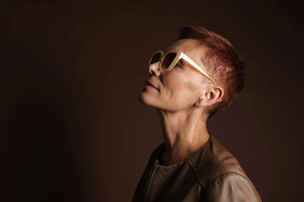 Seniorin Mit Sonnenbrille Posiert Und Blickt Vereinzelt Über Braune Wand — Stockfoto