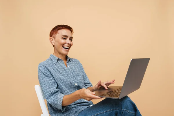 Mulher Gengibre Sênior Trabalhando Com Laptop Enquanto Sentado Cadeira Isolada — Fotografia de Stock