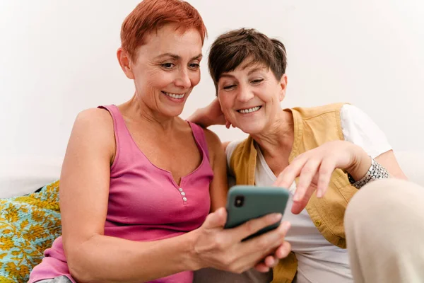 Starší Lesbičky Pár Pomocí Mobilního Telefonu Zatímco Odpočívá Pohovce Společně — Stock fotografie
