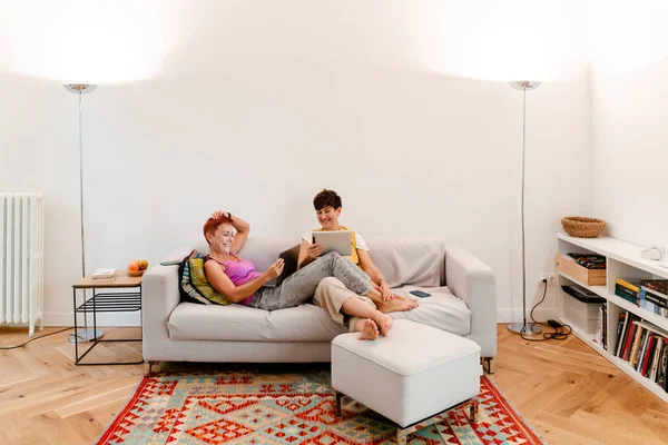 Pasangan Lesbian Dewasa Menggunakan Gadget Sambil Beristirahat Sofa Bersama Rumah — Stok Foto