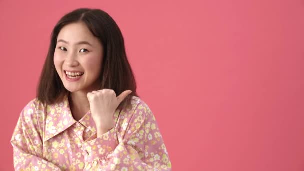 Telif Alanını Gösteren Neşeli Asyalı Kadın Pembe Stüdyoda Göz Kırpıyor — Stok video