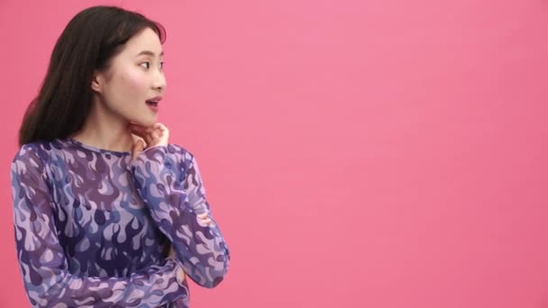Gülen Asyalı Kadın Pembe Stüdyodaki Boşluğu Işaret Ediyor — Stok video