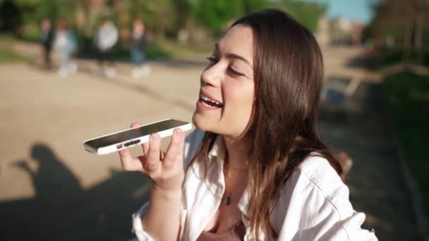 Mulher Morena Positiva Gravando Mensagem Voz Celular Enquanto Sentada Banco — Vídeo de Stock