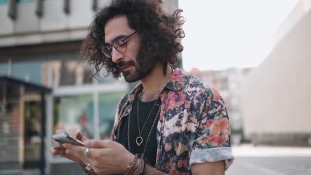 Koncentrerad Lockig Skäggig Man Glasögon Tittar Telefon Och Runt Utomhus — Stockvideo