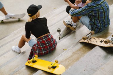 Yaz günü kaykay parkında dinlenirken çok ırklı arkadaşlar konuşuyor.