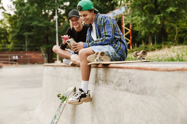 Dos Adolescentes Multirraciales Sonriendo Usando Teléfonos Celulares Mientras Pasan Tiempo —  Fotos de Stock