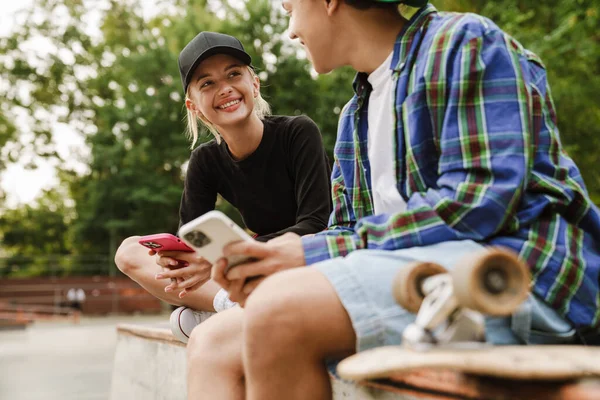 Twee Multiraciale Tieners Glimlachen Het Gebruik Van Mobiele Telefoons Terwijl — Stockfoto