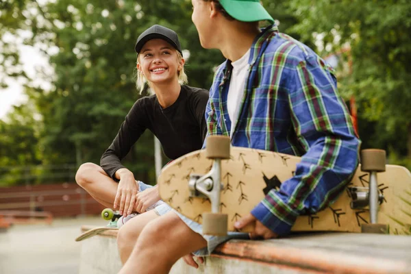 Two Multiracial Teenagers Smiling Using Cellphones While Spending Time Skate — Stock Photo, Image