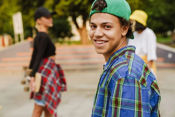 夏の日に彼の友人とスケートパークに乗っている間 ヒスパニック系の男の子は笑顔 — ストック写真