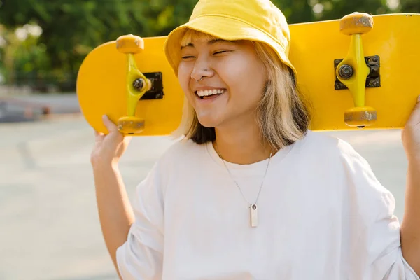 Asiatisk Flicka Bär Hatt Hålla Skateboard Samtidigt Skrattar Utomhus — Stockfoto