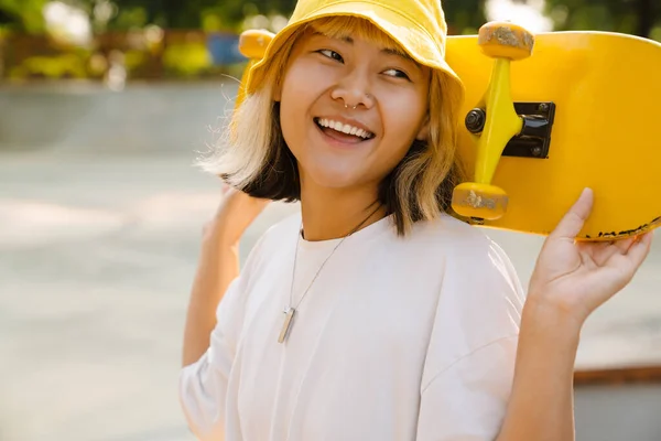 Asiatisk Flicka Bär Hatt Hålla Skateboard Samtidigt Skrattar Utomhus — Stockfoto