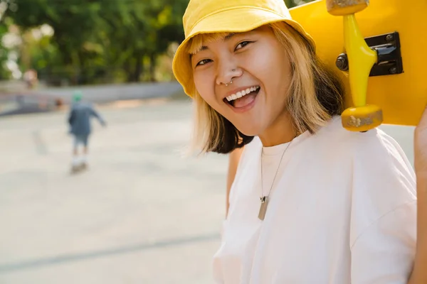 Asiatisk Flicka Bär Hatt Hålla Skateboard Samtidigt Skrattar Utomhus — Stockfoto