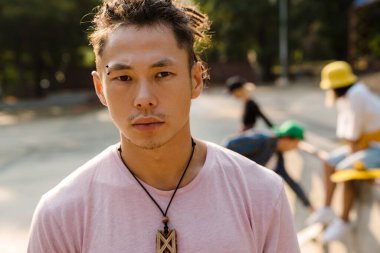 Rastalı Asyalı çocuk arkadaşlarıyla dışarıda kaykay parkında vakit geçiriyor.