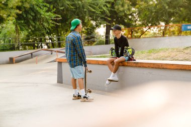 Kaykay parkında zaman geçirirken konuşan ve gülümseyen çok ırklı gençler.