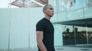 Siyah tişört giyen yakışıklı kel sporcu sabah dışarı çıkıyor.