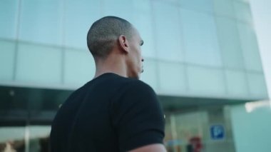 Siyah tişört giyen güçlü kel sporcu sabah dışarı çıkıyor.