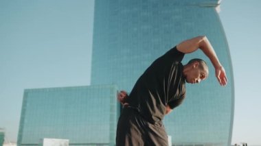 Siyah tişört giyen kendine güvenen kel sporcu sabahları dışarı doğru eğilir.