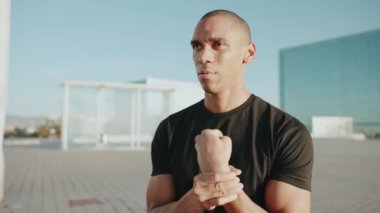 Siyah tişört giyen ciddi kel sporcu sabahları dışarıda ısınıyor.