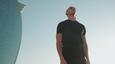 Siyah tişört giyen kel bir sporcu sabahları omuzlarını ısıtır.