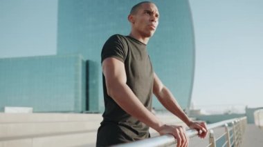 Siyah tişört giyen yakışıklı kel sporcu sabahları dışarı bakıyor.