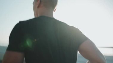 Siyah tişörtlü kel sporcu sabahları dışarıda koşuyor.