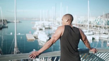 Kel, ciddi bir sporcu siyah tişört giyiyor ve sabahları açık denize bakıyor.