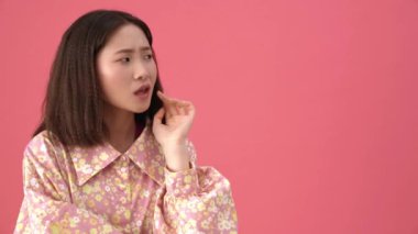 Telif alanına bakıp pembe stüdyoda düşünen neşeli Asyalı kadın.