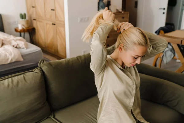 Blonde White Woman Doing Hairstyle While Sitting Sofa Home — Stock Photo, Image