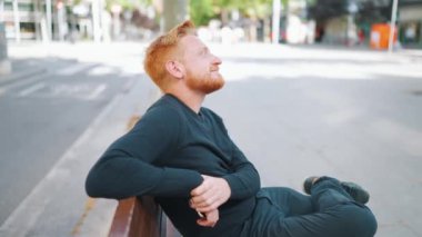 Rahat kızıl adam bankta otururken etrafına bakıyor.