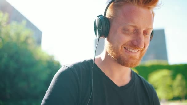 Vrolijke Roodharige Man Die Muziek Hoofdtelefoon Luistert Terwijl Hij Buiten — Stockvideo