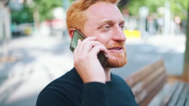 Usmívající Zrzavý Muž Mluví Smartphone Zatímco Sedí Lavičce Venku — Stock video