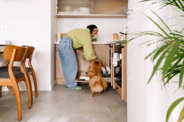 Ev işi yaparken bulaşık makinesi kullanan Asyalı bir kız.