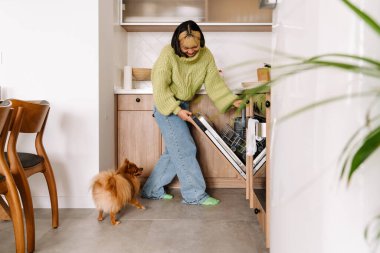 Ev işi yaparken bulaşık makinesi kullanan Asyalı bir kız.