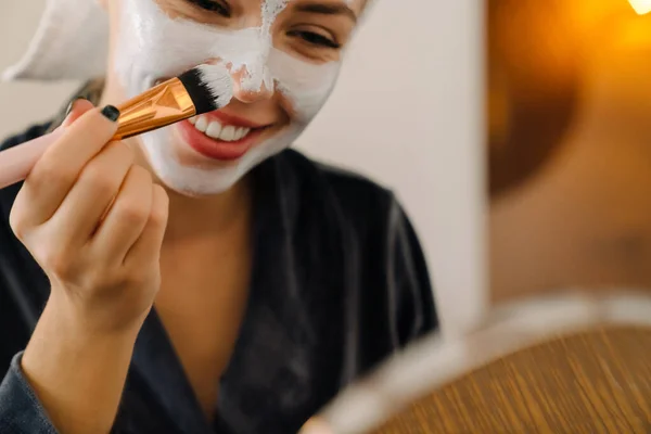 Mujer Blanca Envuelta Toalla Aplicando Mascarilla Mientras Mira Espejo Casa —  Fotos de Stock