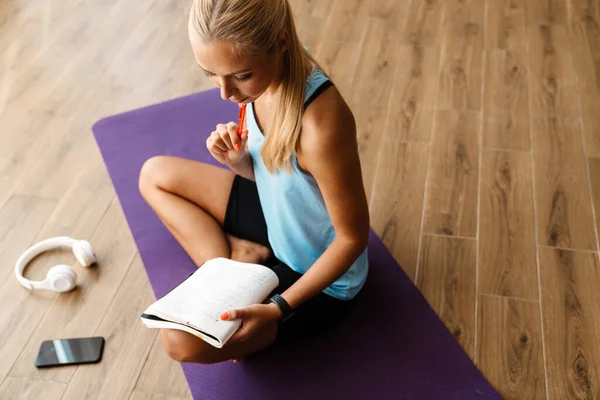 Blonde Junge Frau Schreibt Notizen Beim Yoga Üben Hause — Stockfoto