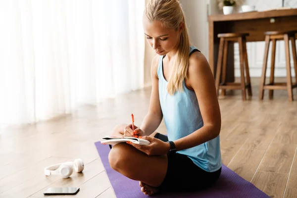 Bionda Giovane Donna Annotare Note Durante Pratica Dello Yoga Casa — Foto Stock