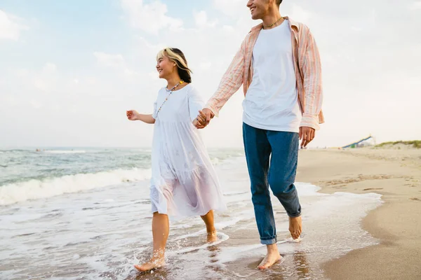 Wielorasowa Para Uśmiechnięta Trzymająca Się Ręce Spacerując Letniej Plaży — Zdjęcie stockowe