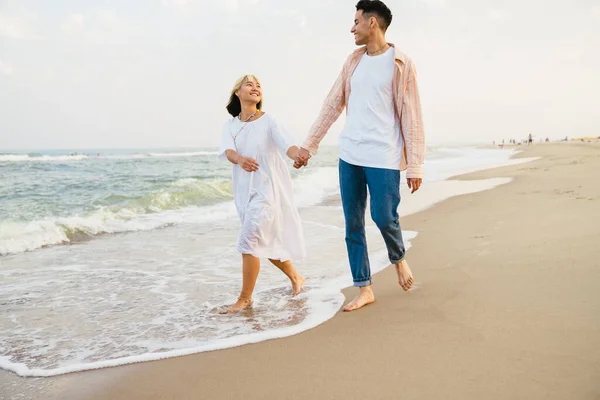 Vielrassiges Paar Lächelt Und Hält Händchen Während Sommerstrand Spaziert — Stockfoto