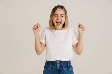 Genç sarışın kadın çığlık atarken, beyaz arka planda izole edilmiş bir jest yapıyor.