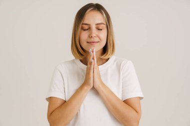 Avuç içlerini bir arada tutarken gülümseyen genç sarışın kadın beyaz arka planda izole edilmiş.