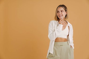 Bej arka planda soyutlanmış, gülümseyen genç sarışın kadın.