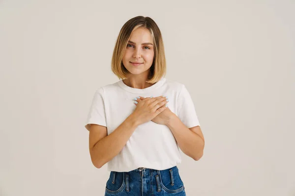 Jovem Loira Sorrindo Enquanto Segura Mãos Seu Peito Isolado Sobre — Fotografia de Stock